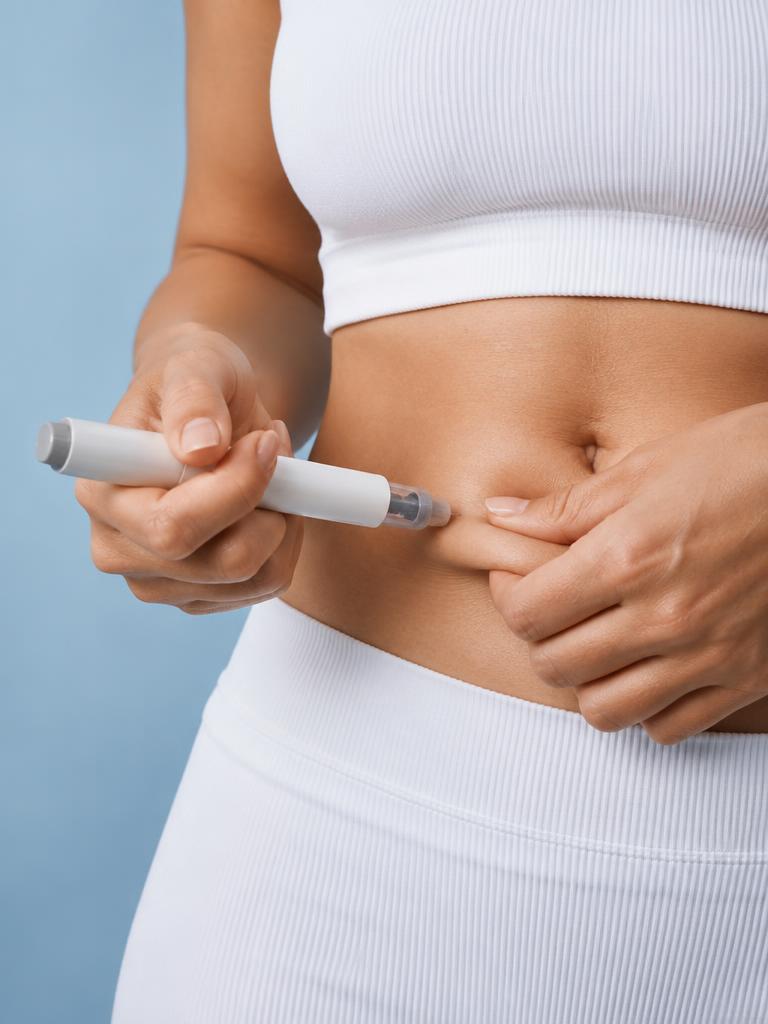 A person holding an injector pen against the abdomen