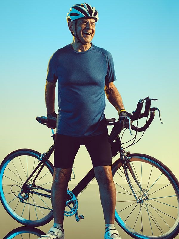 An older man standing with his bicycle outdoors