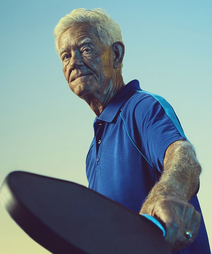 An older man holding a paddle before a game