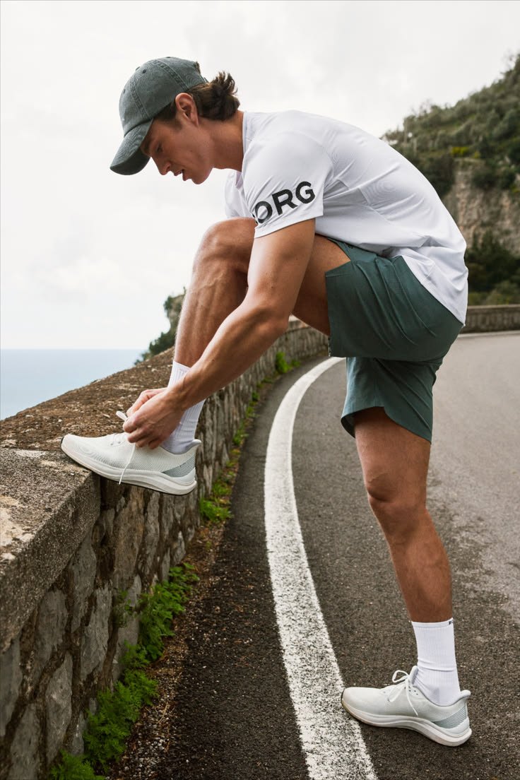 A person tying a running shoe on a coastal road